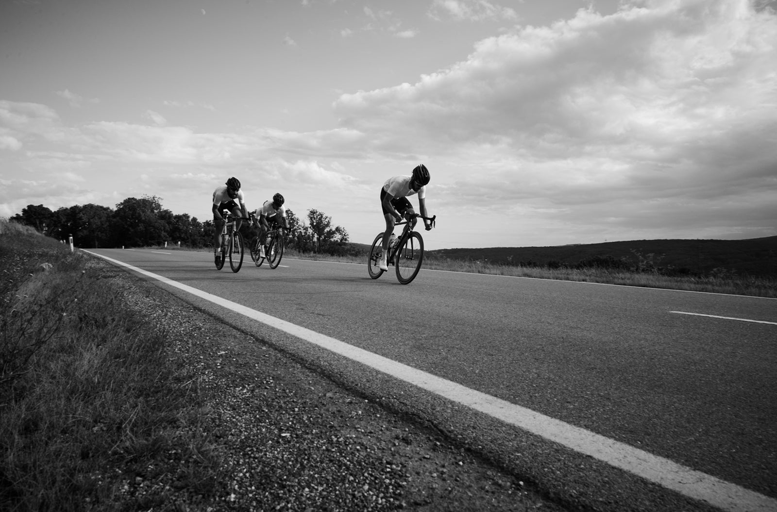 Three cyclists riding together in custom club kit on an open road