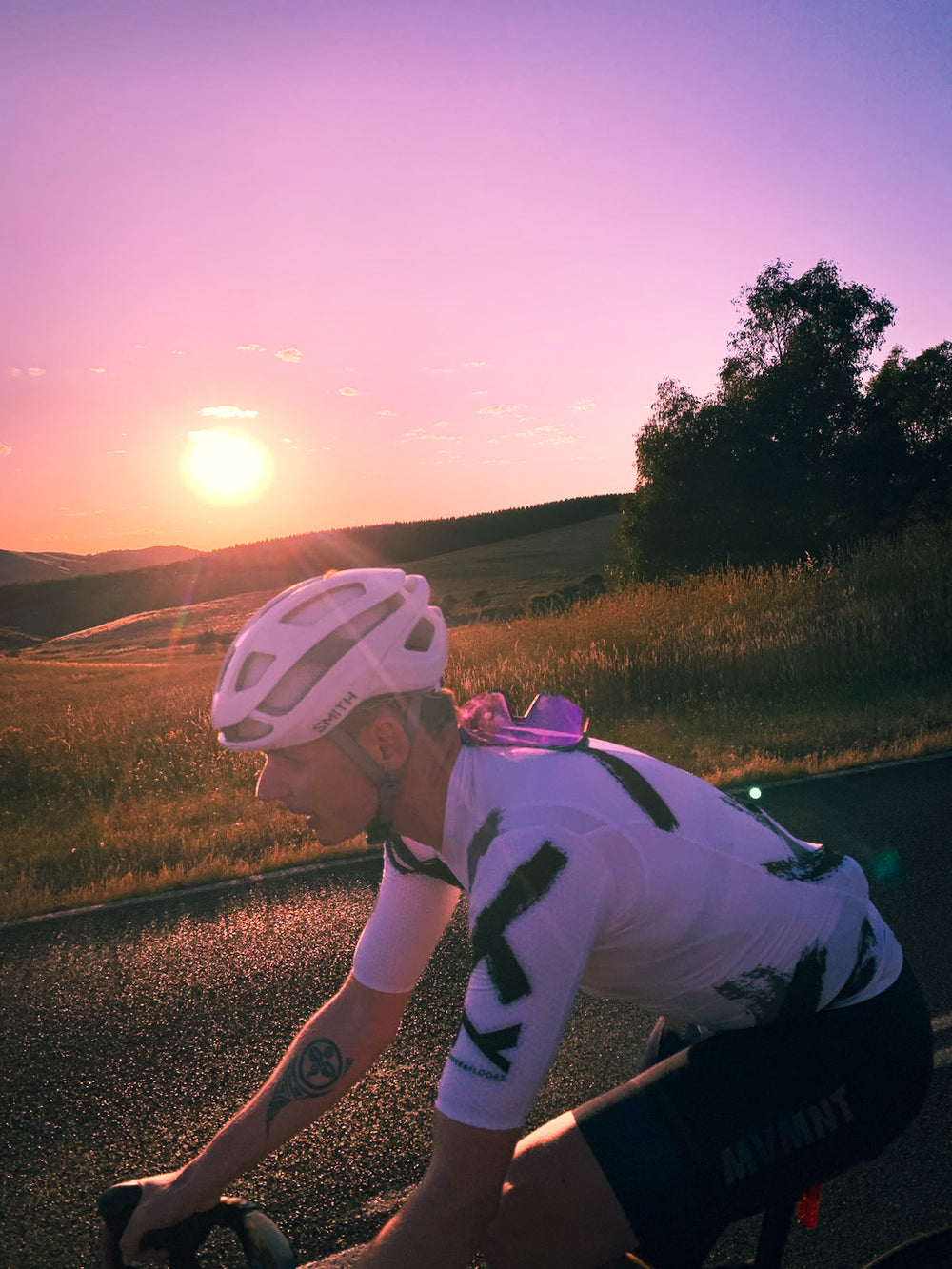 A male cyclist wearing sustainable, premium Aero-Fit cycling clothing rides through the hills of Canberra, his posture embodying power and endurance. The clothing is designed to improve performance and reduce environmental impact, while being perfect for the cycling conditions in Canberra